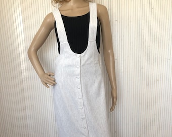 May include: A white linen midi dress with a button-up front and thin straps. The dress has a slight A-line shape and a slit in the front.