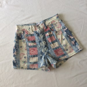 Peut inclure: Un short en jean avec un motif patchwork composé de motifs floraux, paisley et géométriques dans des tons de bleu, rose et blanc.