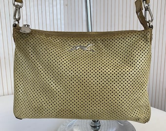 May include: A tan perforated leather crossbody bag with a silver zipper and a silver metal running horse logo. The bag has a long, thin strap and silver hardware. The bag is rectangular and has a small, round zipper pull.
