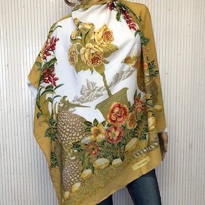 May include: A white silk scarf with a floral and bird design. The scarf is trimmed in gold and has a yellow border. The scarf is made by "La  Venise"