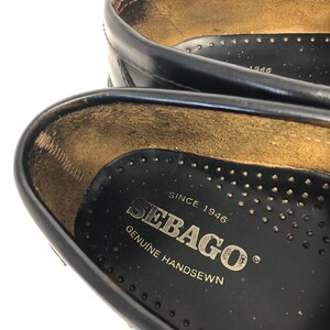 Pu&ograve; includere: Primo piano dell'interno di una scarpa in pelle nera con il testo "Sebago" e "Since 1946 Genuine Handsewn" stampato sulla soletta.