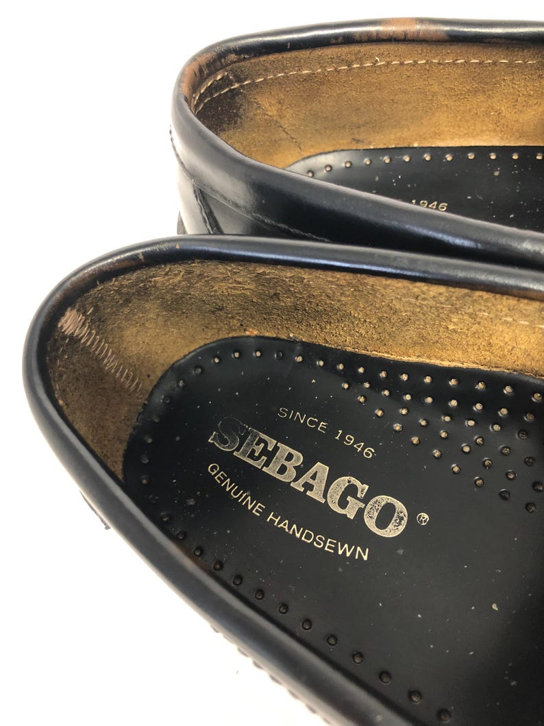 Pu&ograve; includere: Primo piano dell'interno di una scarpa in pelle nera con il testo "Sebago" e "Since 1946 Genuine Handsewn" stampato sulla soletta.