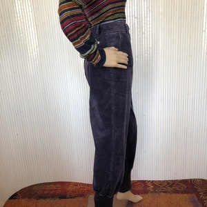 May include: Purple corduroy pants with a cuffed hem. The pants have a relaxed fit and are made of a soft, comfortable fabric.