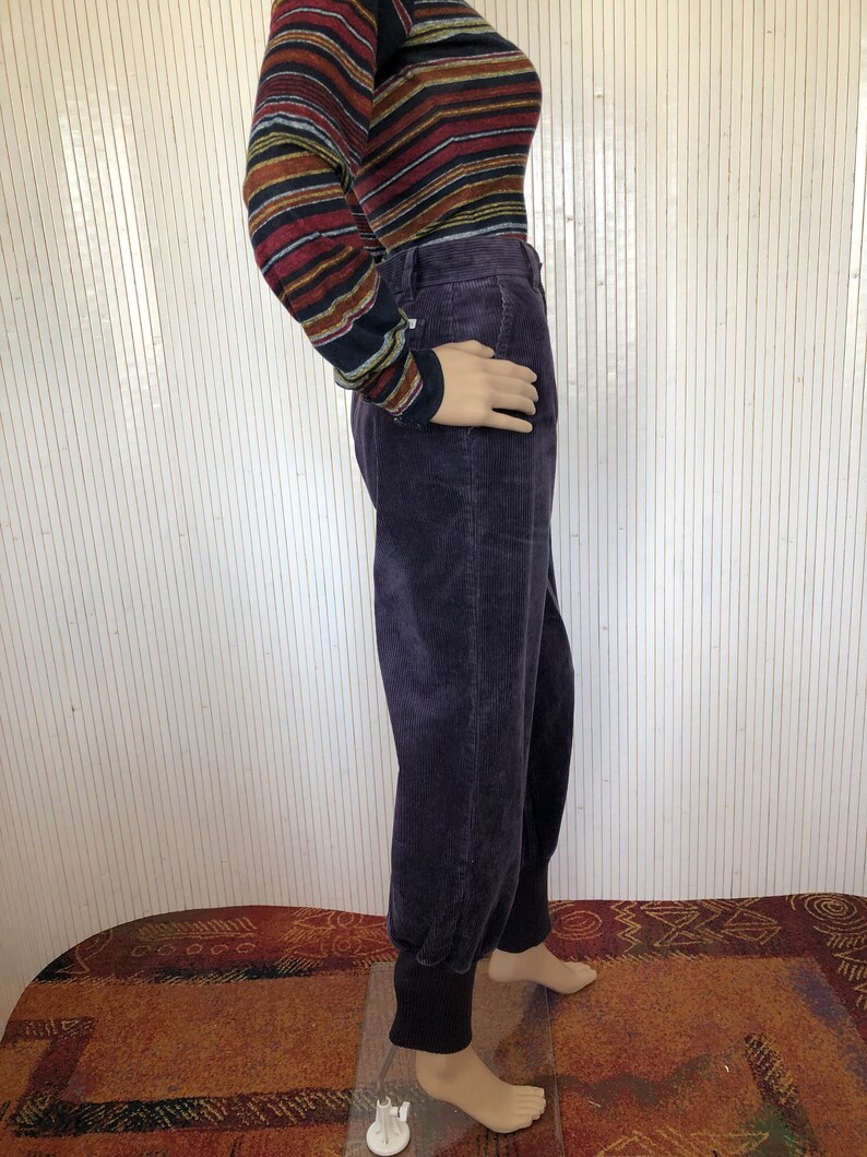 May include: Purple corduroy pants with a cuffed hem. The pants have a relaxed fit and are made of a soft, comfortable fabric.