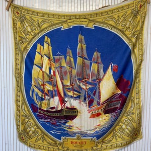 Peut inclure: Un foulard carré présentant une illustration circulaire centrale bleue de deux navires à voile en combat. La bordure est jaune avec des emblèmes dorés décoratifs. Le texte inclut "COMBAT DE L'IMOGENIE CONTRE L'AFRICAINE" et "BOUVET".