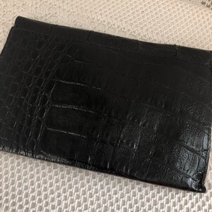 May include: A black leather clutch with a crocodile embossed pattern.