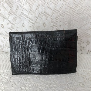 May include: Black crocodile-embossed clutch purse with a flap closure.