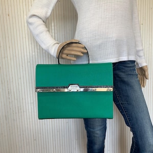 May include: A bright green clutch bag with a silver metal clasp and black trim. The bag has a small silver logo that reads "JOSS & CO."