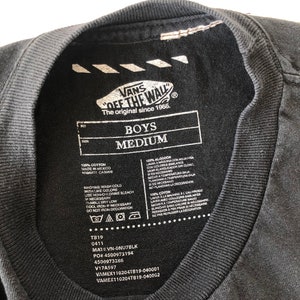 May include: Black t-shirt with a white Vans "Off The Wall" logo and care instructions. The t-shirt is labeled "Boys Medium" and has the text "The original since 1966."
