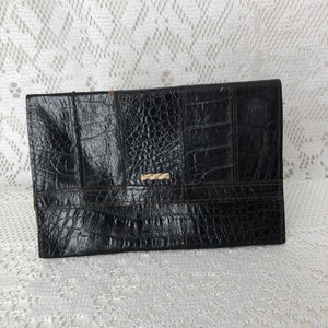 May include: A black leather clutch with a crocodile embossed pattern and a gold clasp.