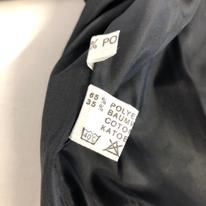 May include: White fabric label with black text indicating the fabric composition: 65% Polyester, 35% Cotton. The label also includes a washing instruction icon for machine wash at 40 degrees Celsius.