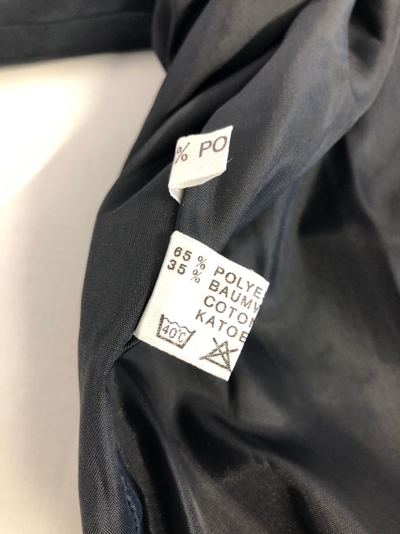 May include: White fabric label with black text indicating the fabric composition: 65% Polyester, 35% Cotton. The label also includes a washing instruction icon for machine wash at 40 degrees Celsius.