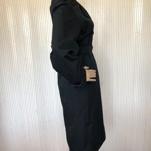 May include: A long black trench coat with a belt and a double breasted closure.