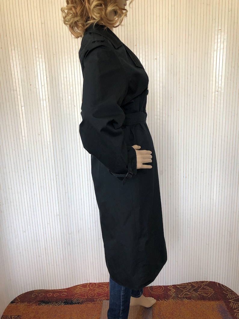 May include: A long black trench coat with a belt and a double breasted closure.