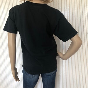 May include: Black short-sleeved t-shirt with a crew neck. The t-shirt is being worn by a mannequin.