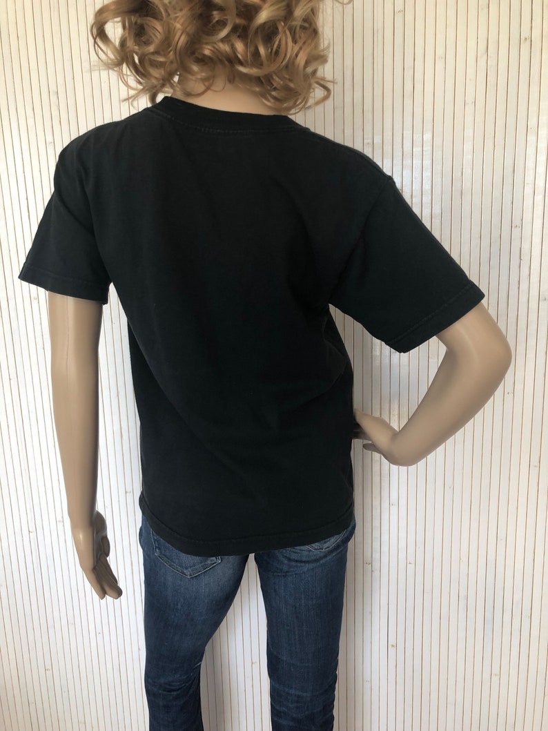 May include: Black short-sleeved t-shirt with a crew neck. The t-shirt is being worn by a mannequin.