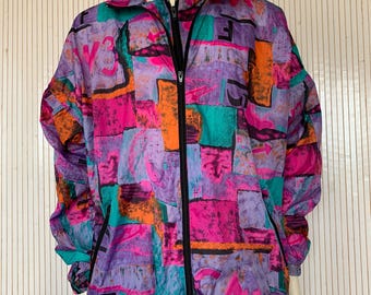 May include: A vintage, full-zip jacket with a vibrant, abstract pattern. The jacket features a mix of colors, including purple, pink, orange, and teal. It has a high collar, black zipper, and black accents. The jacket is displayed on a mannequin.