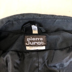 May include: Black leather jacket with a label that reads "Pierre Cardin" and "Made in Belgium". The label also has a size tag that says "42".