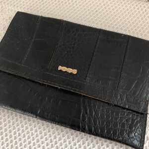 May include: A black leather wallet with a crocodile-embossed pattern and a gold-toned clasp.