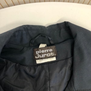 May include: A black jacket with a label that reads "Pierre Jurat" and "Made in Belgium".