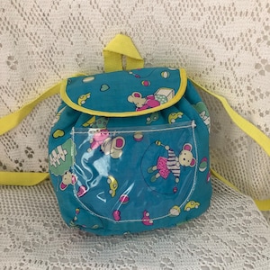 Peut inclure: Un petit sac à dos bleu et jaune avec une poche transparente en plastique sur le devant. Le sac à dos a un motif de souris de dessin animé avec des cœurs, des voitures et des balles.