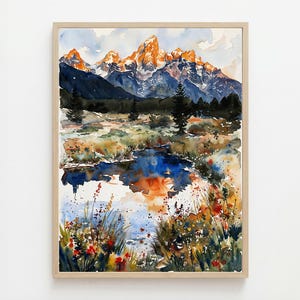 May include: Watercolor painting of a mountain landscape with a lake in the foreground. The mountains have orange and white peaks, with dark blue and purple shadows. The lake reflects the sky and mountains. The painting is framed in a light wood frame.