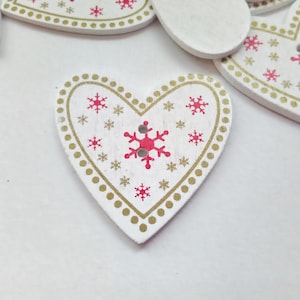 May include: White wooden heart-shaped decorations with a festive design. Each heart features a red snowflake and smaller red snowflakes, surrounded by a gold dotted border. Ideal for festive decorations.
