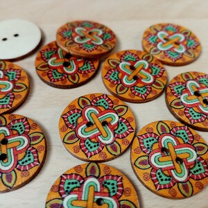 May include: Assortment of 10 wooden buttons with a colourful mandala design. The buttons are round and have two holes. The mandala design features a variety of colours, including orange, red, green, and blue.