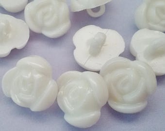 May include: White plastic rose buttons with a raised design. The buttons have two holes and are approximately 1 inch in diameter.