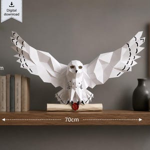 May include: A white geometric paper owl sculpture with spread wings, featuring black markings on the wings and chest, holding a scroll with a red wax seal. The sculpture measures 35 cm in height and 70 cm in width, presented as a digital download.