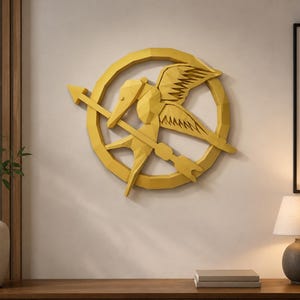 May include: A yellow wall-mounted decorative piece featuring a geometric, low-poly style design of a bird in flight holding an arrow within a circular frame. The object has a faceted, three-dimensional appearance with sharp, angular edges.