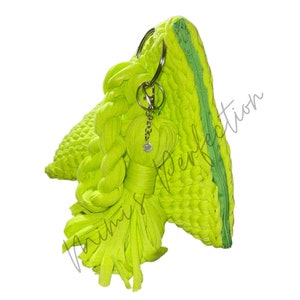 May include: A bright neon green handbag with a braided handle and a matching tassel. The bag features a zipper closure and silver-toned metal rings. The bag is made of a textured fabric.