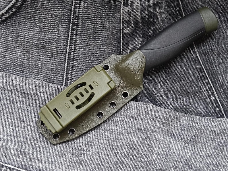 May include: A green and black knife with a plastic sheath. The sheath has a belt loop and multiple holes for attaching to a belt.