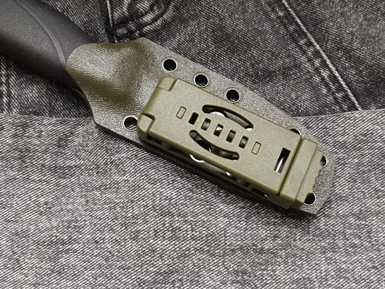 May include: A green knife sheath with a black knife handle. The sheath has a clip on the back and a series of holes for attaching to a belt.