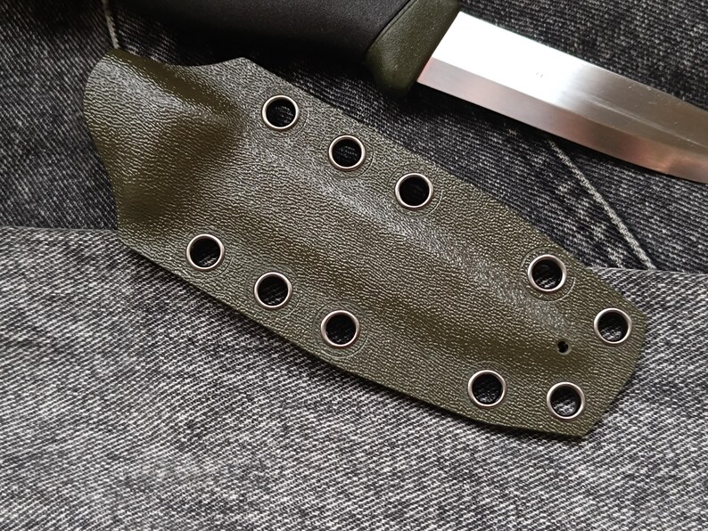 May include: A dark green leather knife sheath with multiple metal eyelets.