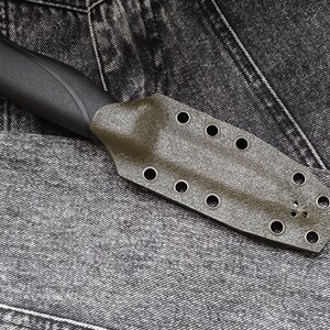 May include: A dark green knife sheath with multiple eyelets. The sheath is made of a textured material and has a black handle.