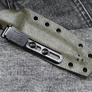 May include: A green leather knife sheath with a black metal clip. The clip has the text "ULTRACLIP" on it. The sheath has multiple holes around the edge.