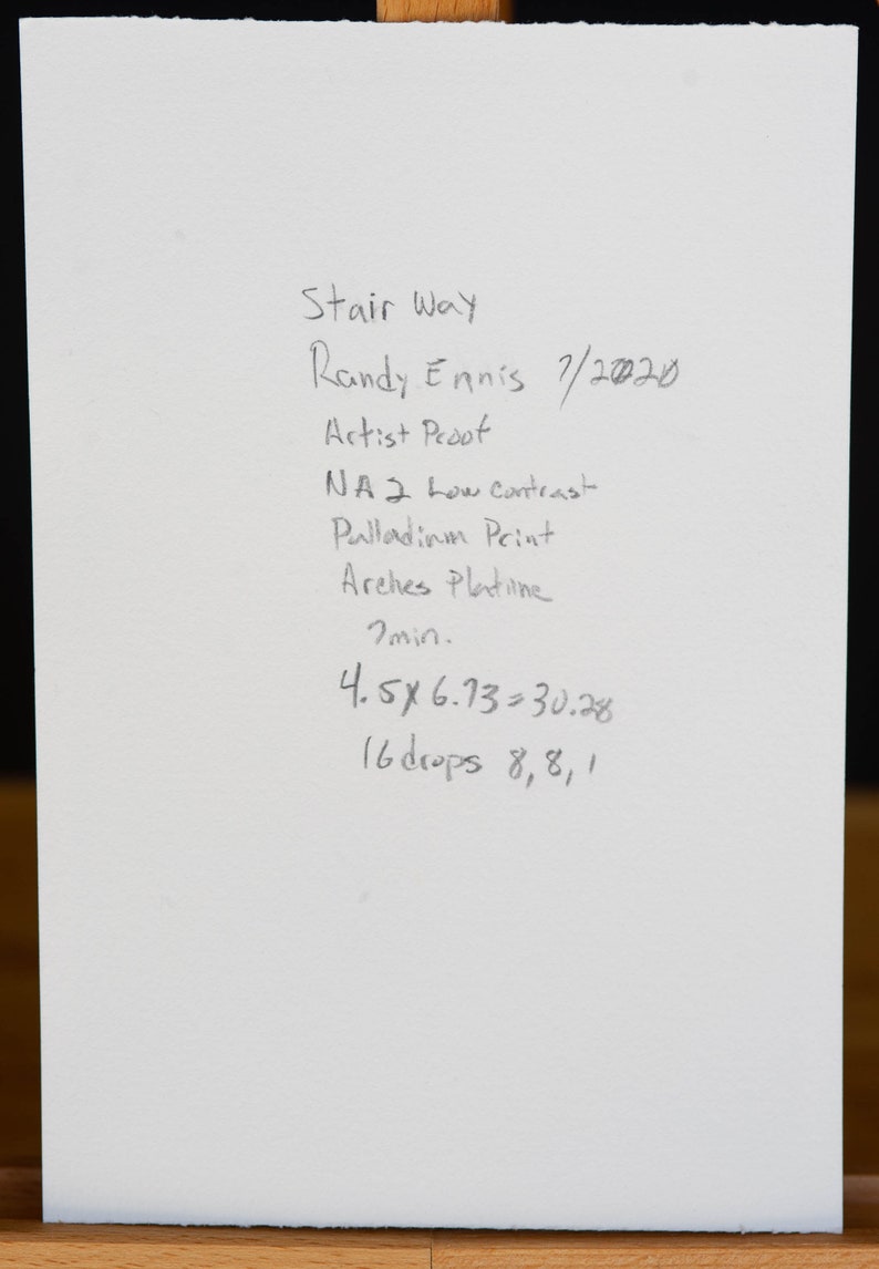 May include: A handwritten note on white paper with the title "Stair Way" and the artist's name "Randy Ennis". The note includes the date "7/2020", the words "Artist Proof", "NA 2 Low Contrast", "Palladium Print", "Arches Platine", "7 min", "4.5 x 6.73 = 30.28", and "16 drops 8, 8, 1".