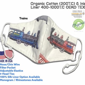 May include: White face mask with a colorful train pattern. The mask is made of organic cotton and has a 400-1000 thread count liner. It is OEKO-TEX certified and made in the USA. The mask has a nose wire, filter pocket, adjustable elastic straps, and a 100% silk liner option. It is also available with a monogram or rhinestones.