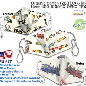 May include: Three white face masks with different designs. The first mask has a truck pattern, the second mask has a car pattern, and the third mask has a train pattern. The masks are made of organic cotton and have a silk liner option. The masks are made in the USA and are OEKO-TEX certified.