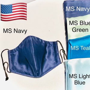May include: A navy blue satin face mask with adjustable ear loops. The mask is shown against a white background with swatches of fabric in various shades of blue and green labeled with the color names "MS Navy", "MS Blue Green", "MS Teal", and "MS Light Blue".