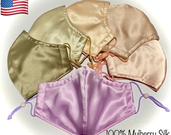 May include: Five face masks made of 100% mulberry silk in various shades of beige, pink, and lavender. The masks are arranged in a semi-circle with the text "100% Mulberry Silk" at the bottom.