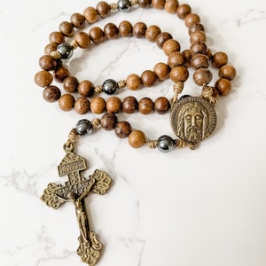 Catholic rosary made with brown robles wood beads, hematite beads, bronze tone Pardon crucifix, bronze tone Holy Face medal, and micro cord