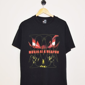 May include: Black t-shirt with a graphic print of a red and yellow "W" with the text "Music as a Weapon" underneath.