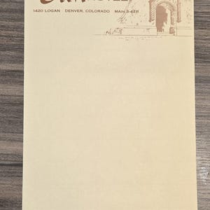 May include: Cream-colored notepad with the text "Olin HOTEL" in brown script. The notepad also includes the address "1420 LOGAN DENVER, COLORADO MAIN 3-4211" and a small architectural illustration.