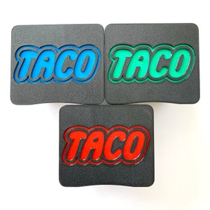 May include: Three black rectangular coasters with the word "TACO" in raised letters. The coasters are in blue, green, and red.
