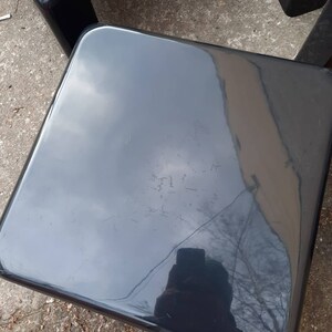 May include: Two black plastic chairs with a glossy finish. The chairs are square and have a simple design.