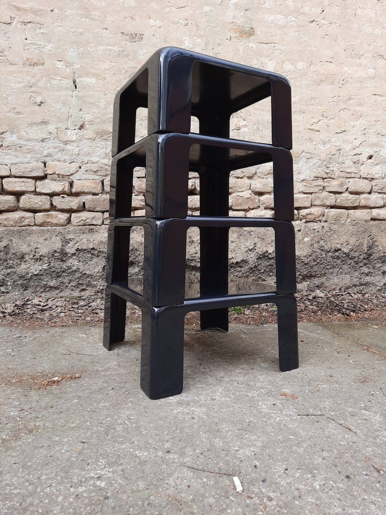 May include: A set of three black, stackable, plastic side tables with a modern design.