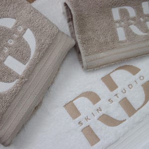 Charcoal textured towel with a circular badge emblem featuring a lightning bolt icon, embroidered in white thread for a bold, modern branding design.