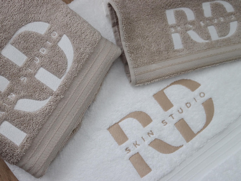Charcoal textured towel with a circular badge emblem featuring a lightning bolt icon, embroidered in white thread for a bold, modern branding design.